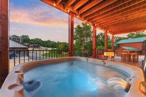 A hot tub under a wooden pergola with string lights, surrounded by a deck with outdoor furniture. - This One Books Fast - Hot Tub, Boat Slip, Bonus Rm (Branson)