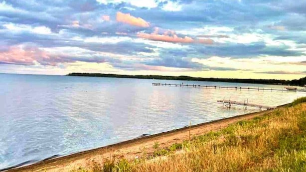 A coastal landscape with a calm sea, a wooden pier, and grassy areas. - Pet-Friendly Garrison Cabin (Garrison)