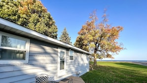 A single-story house with a patio area featuring a metal table and chairs. - Pet-Friendly Garrison Cabin (Garrison)