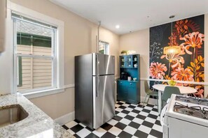 A compact kitchen with a stainless steel refrigerator, a gas stove, a sink, and a checkered floor. - Garden Getaway 2BR Minutes to Salem, Beach, and train to Boston! (Beverly)
