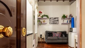 A living room with a sofa, a coffee table, a small side table, a bookshelf, and a framed picture on the wall. - GuestHost - Apartment located on the ground floor of a renovated period building. There are 5 steps to reach the floor and 1 step at the entrance.It comfortably accommodates two people in 40 m2 of space, the apartment is located a few steps from the wond (Roma)
