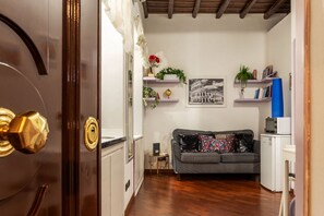 A living room with a sofa, a coffee table, a small side table, a bookshelf, and a framed picture on the wall. - GuestHost - Apartment located on the ground floor of a renovated period building. There are 5 steps to reach the floor and 1 step at the entrance.It comfortably accommodates two people in 40 m2 of space, the apartment is located a few steps from the wond (Roma)