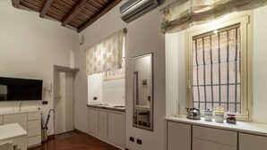 A kitchen with white cabinets, a wooden floor, a window with bars, and a TV mounted on the wall. - GuestHost - Apartment located on the ground floor of a renovated period building. There are 5 steps to reach the floor and 1 step at the entrance.It comfortably accommodates two people in 40 m2 of space, the apartment is located a few steps from the wond (Roma)
