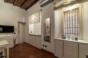 A kitchen with white cabinets, a wooden floor, a window with bars, and a TV mounted on the wall. - GuestHost - Apartment located on the ground floor of a renovated period building. There are 5 steps to reach the floor and 1 step at the entrance.It comfortably accommodates two people in 40 m2 of space, the apartment is located a few steps from the wond (Roma)