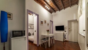A compact living space with a kitchenette, a dining area, and a TV mounted on the wall. - GuestHost - Apartment located on the ground floor of a renovated period building. There are 5 steps to reach the floor and 1 step at the entrance.It comfortably accommodates two people in 40 m2 of space, the apartment is located a few steps from the wond (Roma)