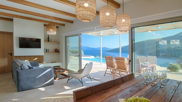 Una sala de estar moderna con una mesa de comedor de madera, asientos cómodos y un amplio ventanal con vistas panorámicas.