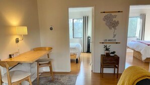 A compact living space with a dining area, a bed, a small table with a plant, and a wall with a Los Angeles sign.