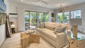 A modern living room with a beige sofa, a glass coffee table, and a ceiling fan.