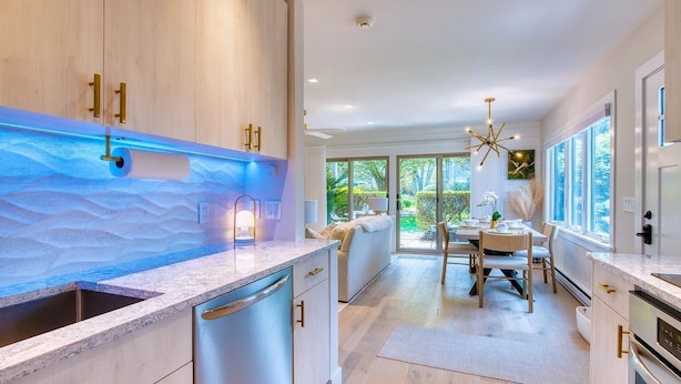 A modern kitchen with a large island, wooden cabinets, and a view to the outdoor dining area.