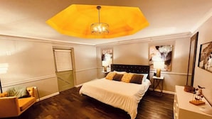 A hotel room with a large bed, a wooden floor, a desk, a chair, and a unique ceiling light fixture. - Suite 206 - Starry Night at Rock Spring Resort near Chattanooga (Rock Spring)