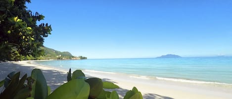 På stranden, vit sandstrand, solstolar och strandhanddukar