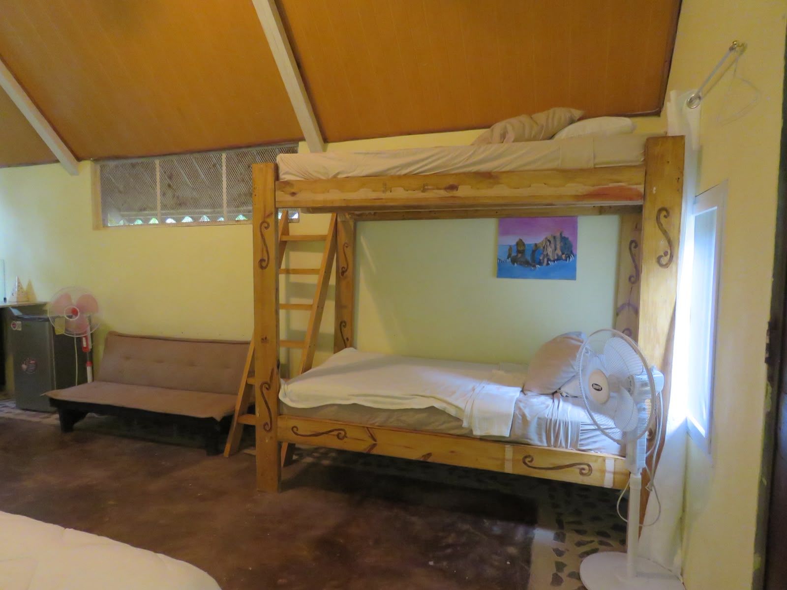 A bunk bed with a ladder, a small desk, and a fan.