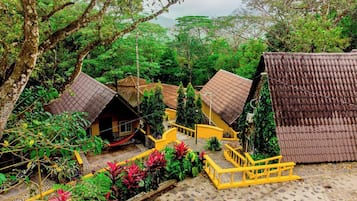 A traditional village with thatched-roof huts, a stone-paved courtyard, and lush greenery.