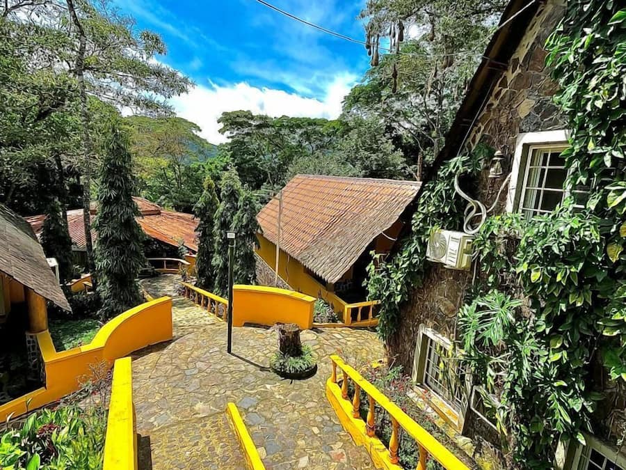 A courtyard with yellow railings, stone flooring, and buildings with red-tiled roofs.