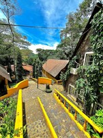 Un patio con barandillas amarillas, suelo de piedra y edificios con tejados de tejas rojas.