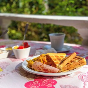En tallerken med en sandwich og en kop på et bord med et blomstret borddække.