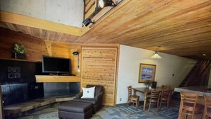 A cozy living room with a fireplace, a television, and a dining area with wooden chairs and a table. - Amazing two story loft condo at Snowbird, UT: March 21-28, 2026: Timeshare. (Snowbird)