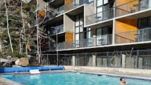 A swimming pool adjacent to a multi-story building with balconies. - Amazing two story loft condo at Snowbird, UT: March 21-28, 2026: Timeshare. (Snowbird)
