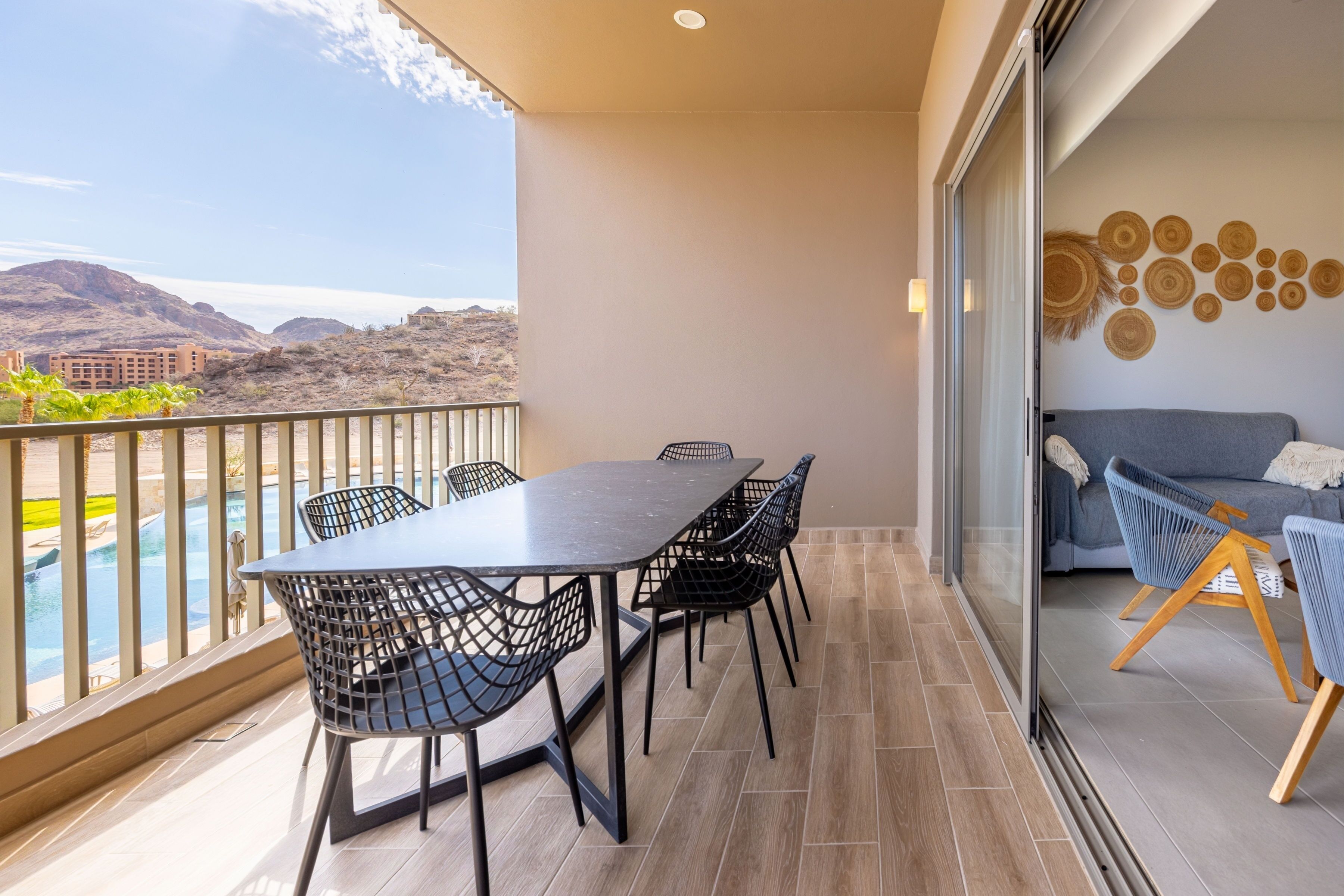 A balcony with a dining table and chairs, a sofa, and a decorative wall.