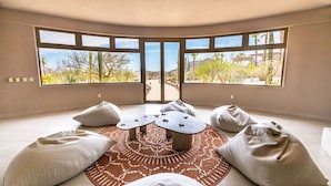 A room with a large window, a round table, and several bean bag chairs.