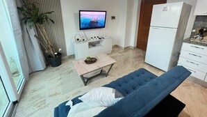 Un soggiorno moderno con un divano, un tavolino, una televisione e un frigorifero.