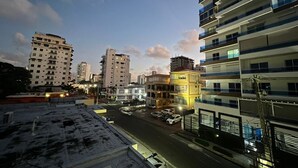 Paesaggio urbano al crepuscolo con grattacieli, un'area di parcheggio e una strada con veicoli.
