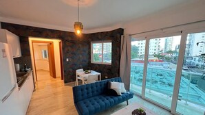 Un appartamento moderno con un divano blu, un tavolo da pranzo e un angolo cottura.