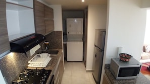 Una cucina compatta con piano cottura a gas, forno a microonde, frigorifero e lavello.