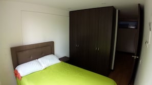 Una stanza con un letto, un armadio e una porta che dà su un'altra stanza.
