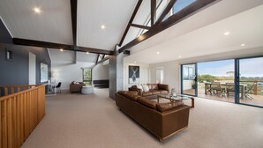 A spacious living area with a large brown leather sofa, a glass coffee table, and a dining area with outdoor seating.