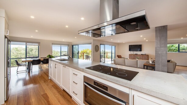 A modern kitchen with a central island, built-in oven, and a large window overlooking a balcony.