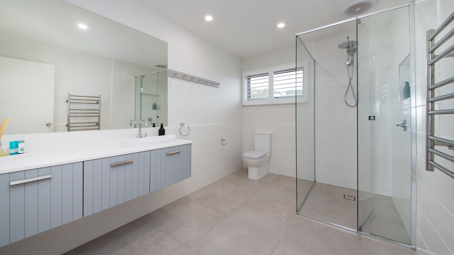Une salle de bain moderne avec une douche à parois de verre, un grand miroir et un lavabo blanc avec un meuble-vasque.