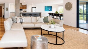 A modern living room with a sectional sofa, a round coffee table, and a staircase.