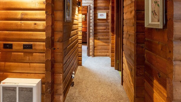 L’intérieur d ’une cabane en rondins, avec un couloir central, des murs en bois et un plancher recouvert de moquette.