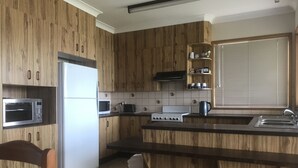 Una cocina con armarios de madera, un refrigerador, un microondas, una estufa y un lavamanos.