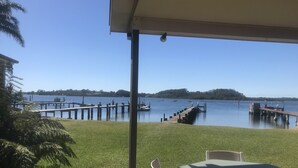 Un patio con mesa y sillas que da a un lago con muelles y barcos.