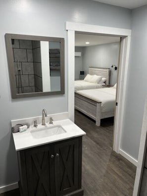 A bathroom with a white sink, dark cabinets, and a mirror.