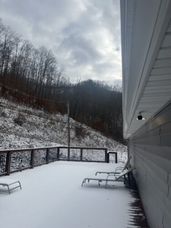 A covered outdoor area with a metal railing, a bench, and a snow-covered landscape.
