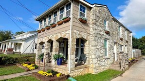 Una casa de piedra con un porche, ventanas y macetas de flores.