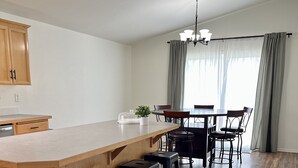 Ett modernt kök med en köksö i trä, barstolar och en matplats med en kristallkrona.
