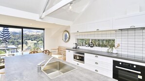 Een moderne keuken met een groot eiland, witte kasten en uitzicht op het platteland.