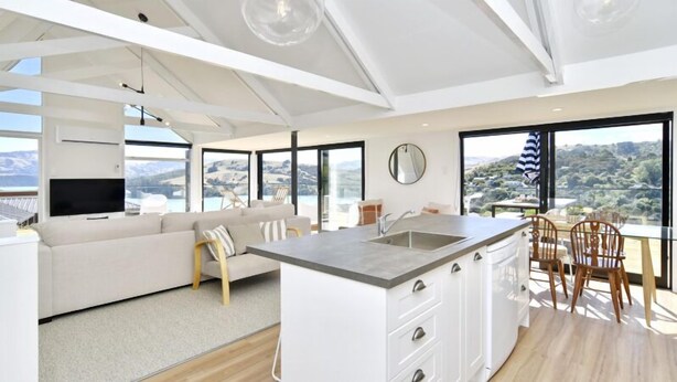Een moderne keuken met een centraal eiland, witte kasten en een groot raam met een prachtig uitzicht.