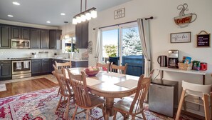 A modern kitchen with dark cabinets, a central island, and a dining area with wooden chairs and a table.