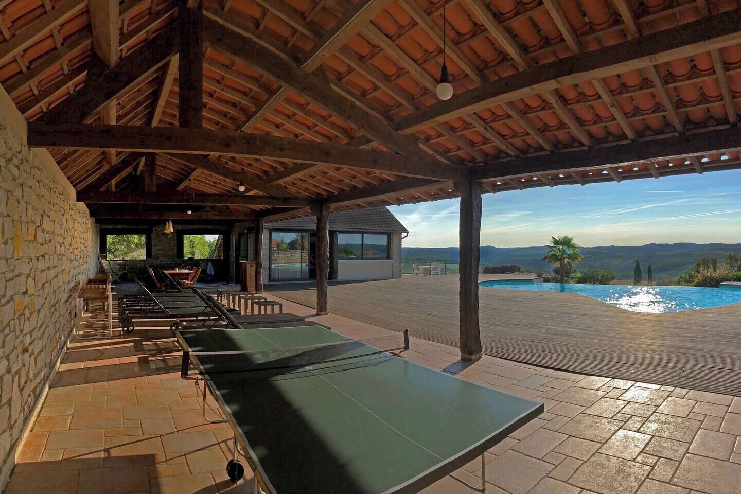 An outdoor pool area with a covered seating area and a view of the landscape.
