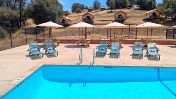 Una piscina al aire libre, sombrillas, sillones reclinables de piscina