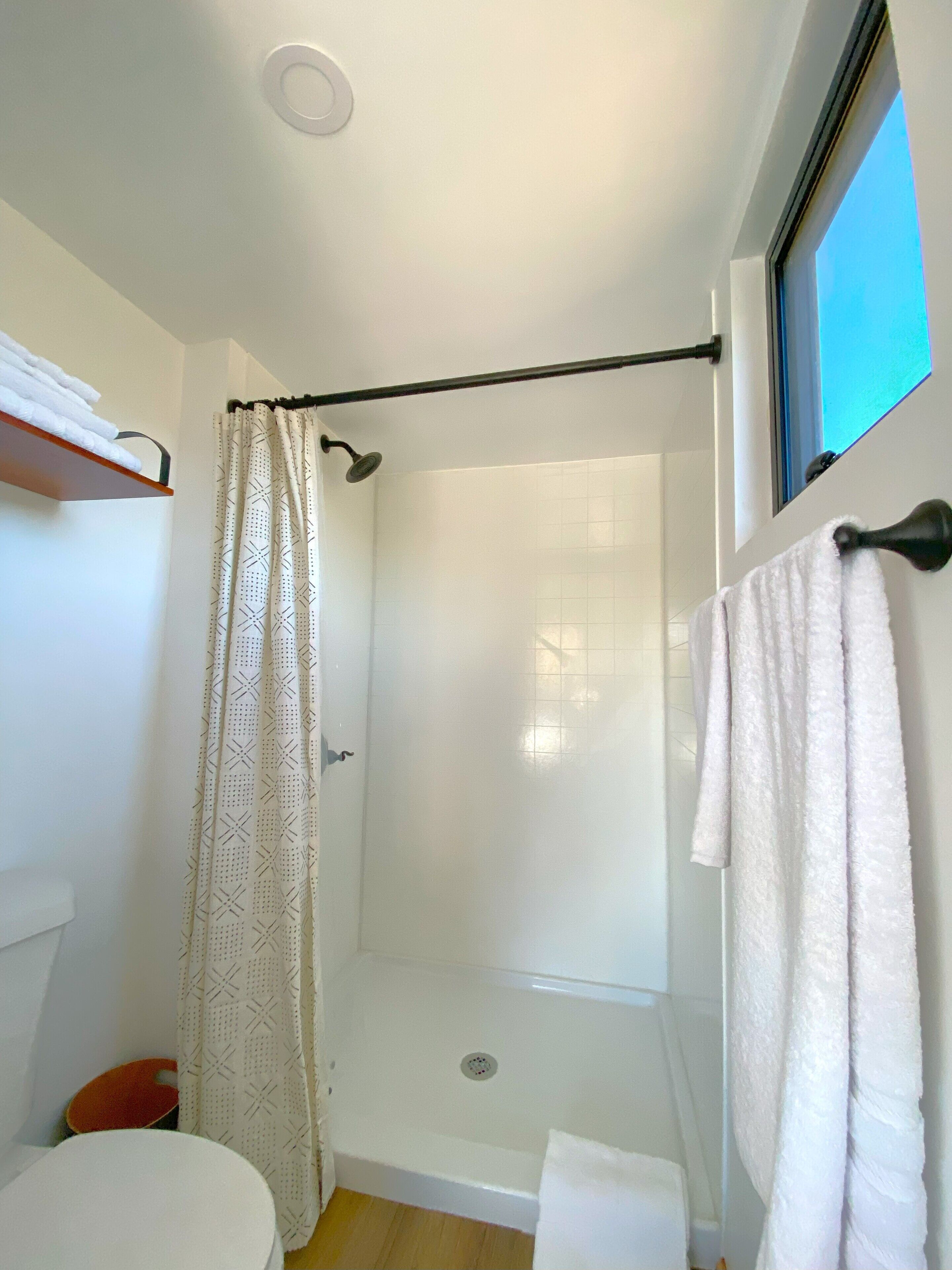 A shower area with a glass door, a towel rack with a towel, and a window with a view.