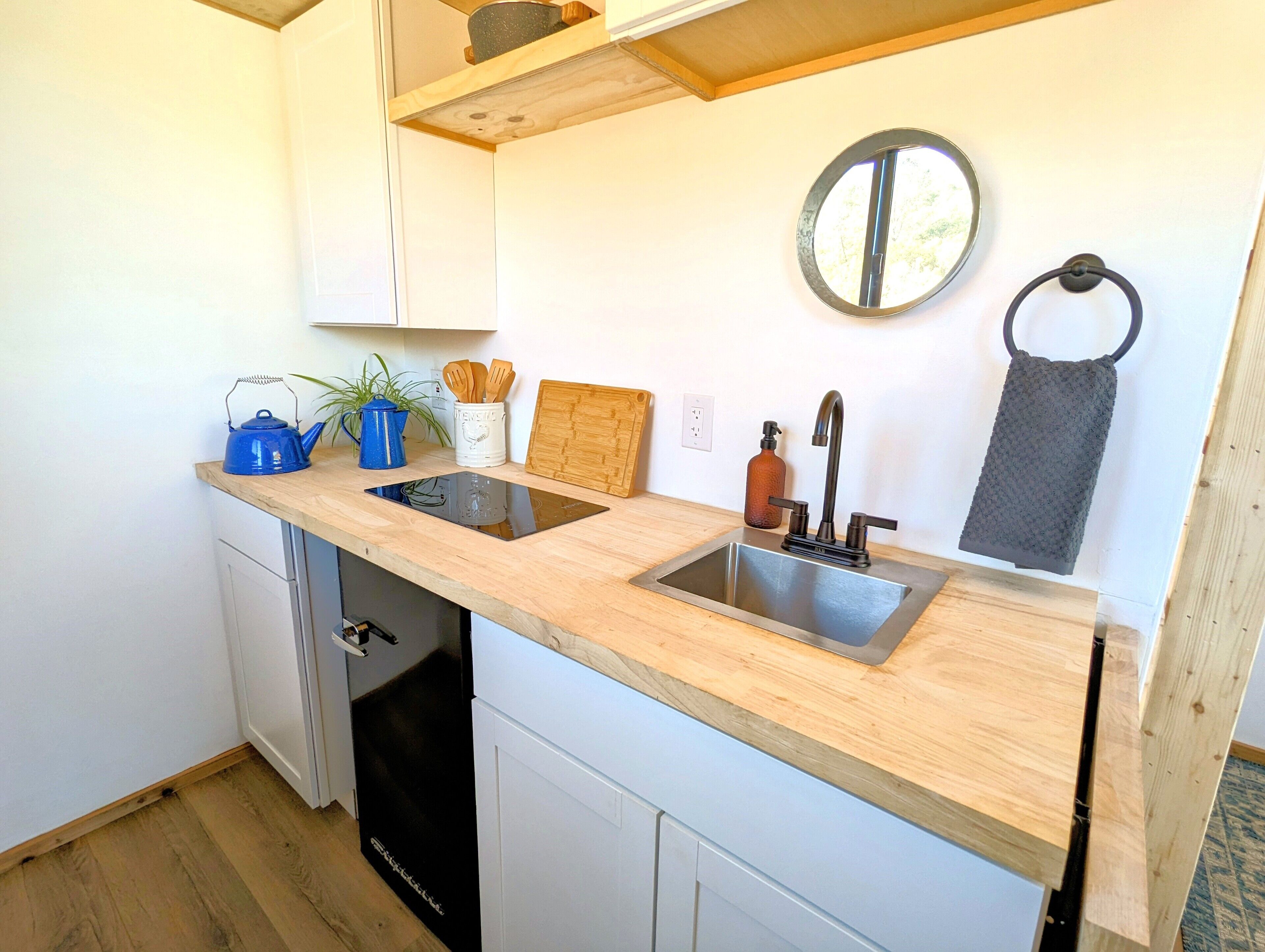 A compact kitchen with a double sink, wooden countertop, and a dishwasher.