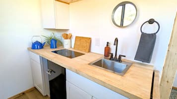 A compact kitchen with a double sink, wooden countertop, and a dishwasher.