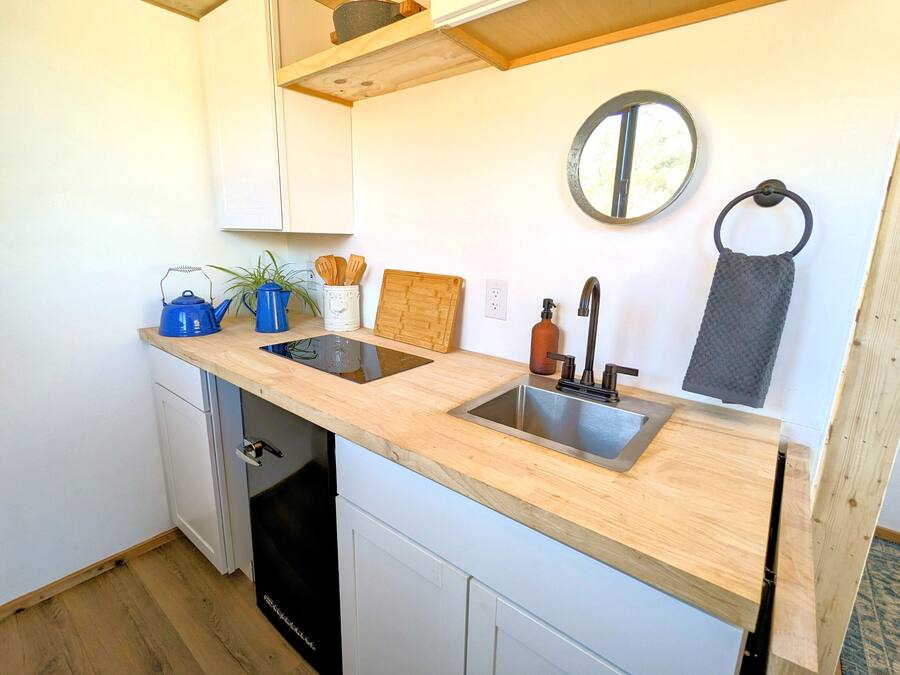 A compact kitchen with a double sink, wooden countertop, and a dishwasher.