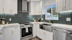 Una cocina moderna con gabinetes blancos, un lavamanos de acero inoxidable y un salpicadero con estampado blanco y negro.